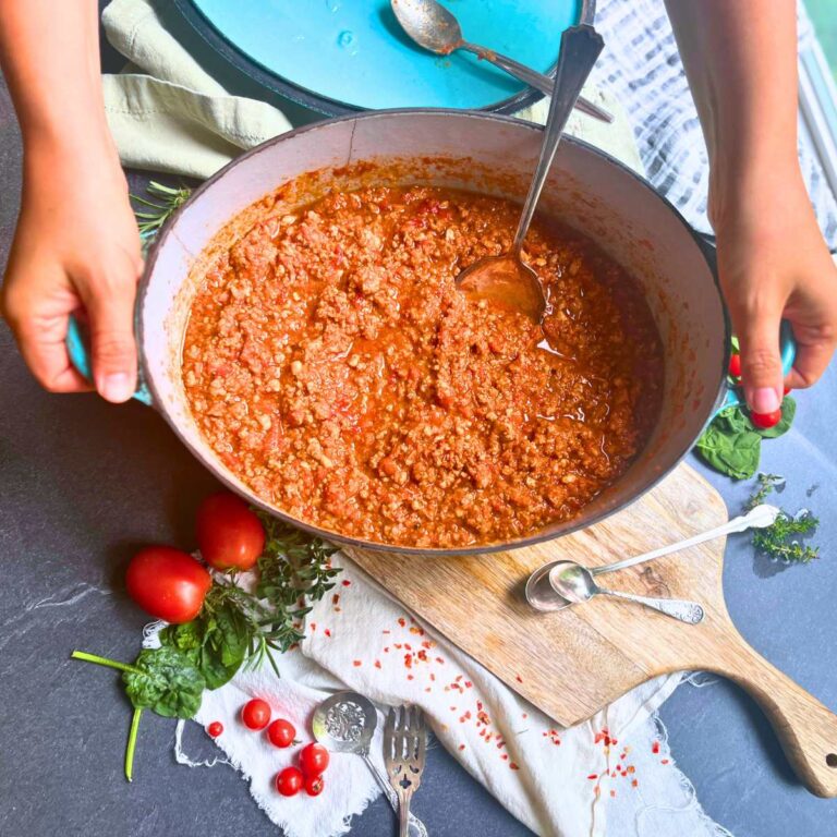 A woman is holding a large Dutch oven full of beef ragu.
