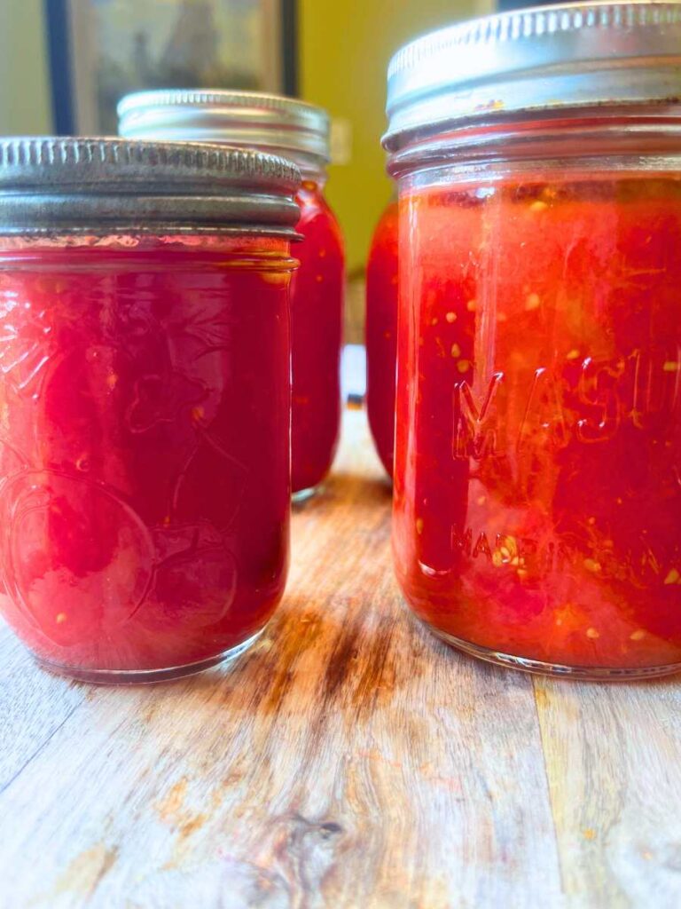 A side view of canning jars filled with tomato sauce.