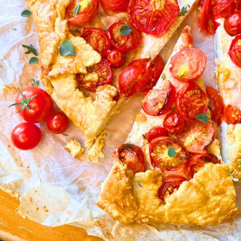 A sliced tomato and cheese galette on a piece of parchment paper.