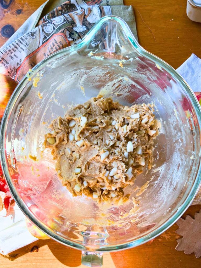 A glass bowl with apple loaf cake batter inside.