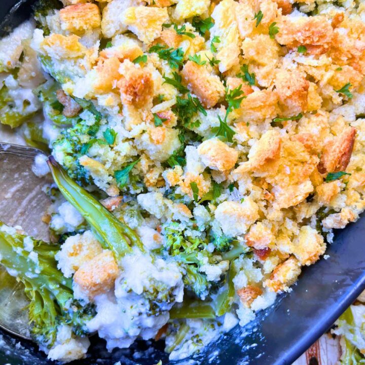 An overhead look at a broccoli au Gratin casserole. There is a metal serving spoon inside.