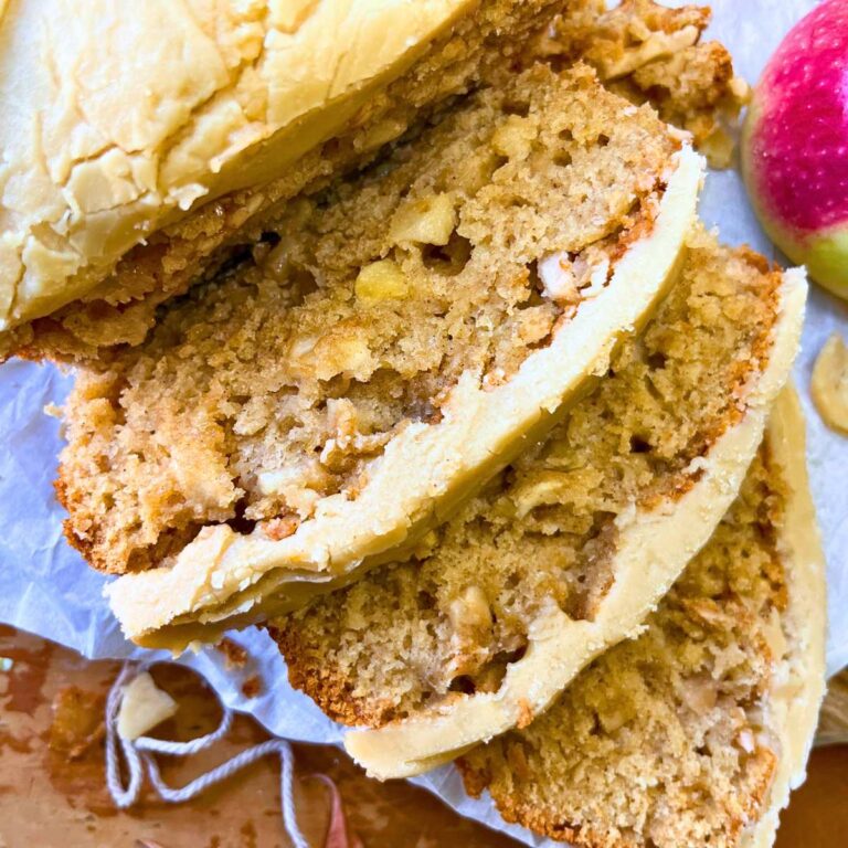 A sliced apple loaf cake with caramel icing on top.