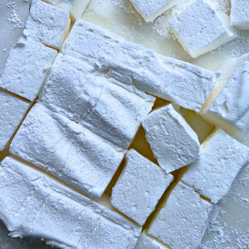 Square cut homemade marshmallows on a piece of parchment paper.