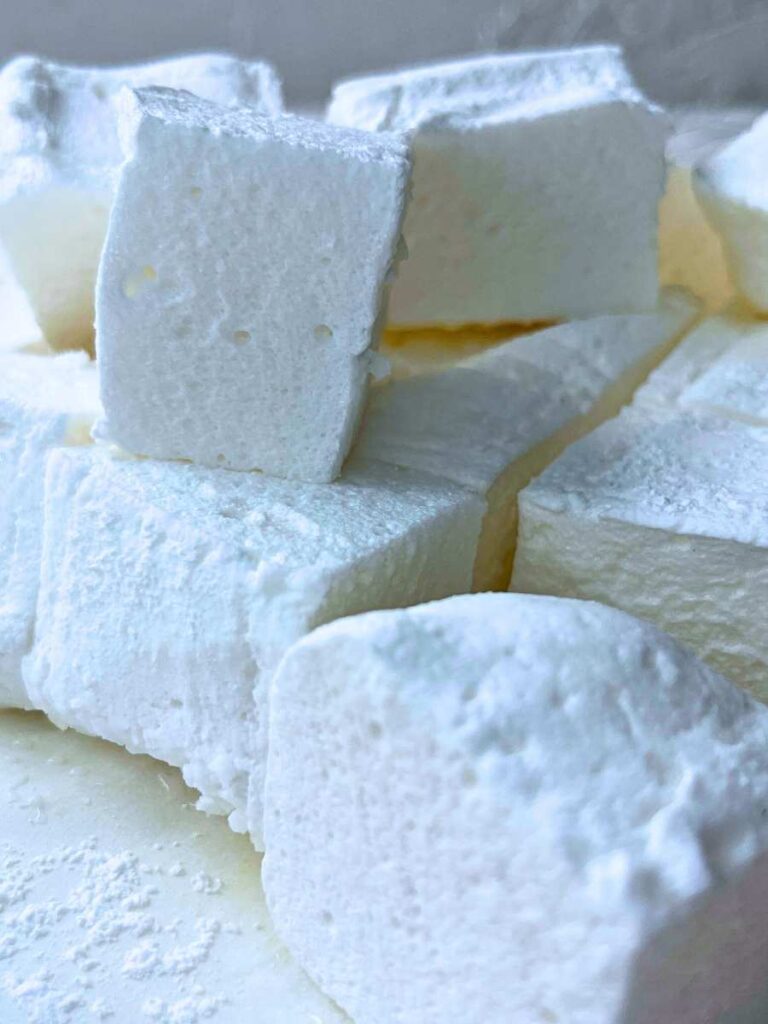 Square-cut homemade marshmallows. Some are stacked.