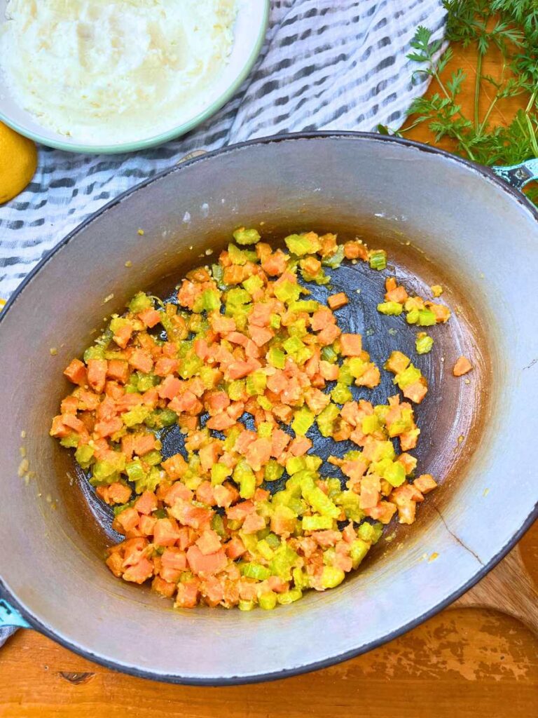 A Dutch oven with cooked diced vegetables with a cooked flour coating.