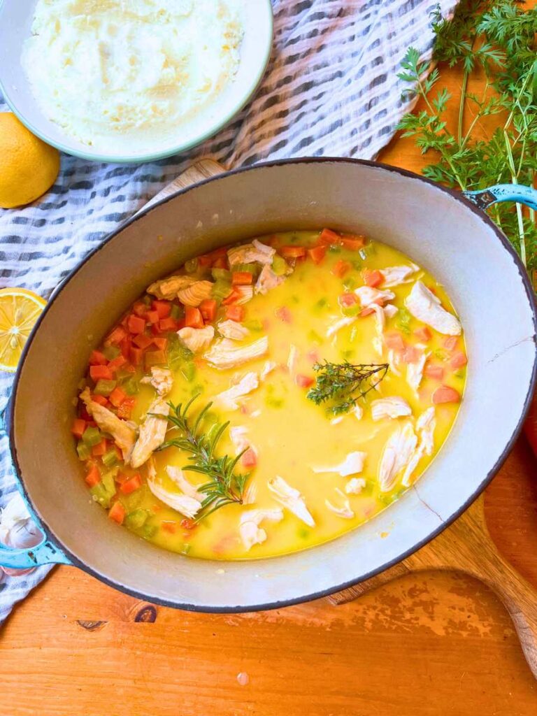 A Dutch oven with cooked turkey and vegetables in broth.