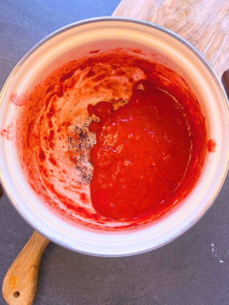 A white sauce pot with strawberry purée inside.