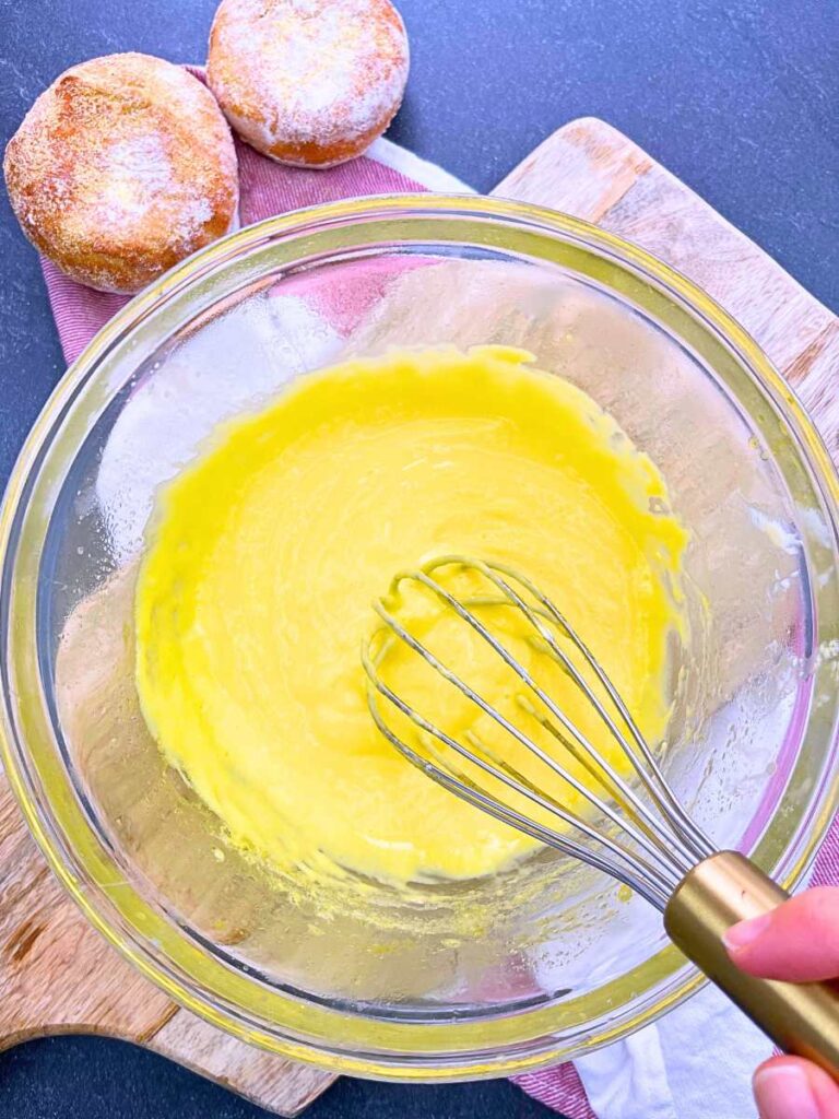 A woman is whisking a thickened hollandaise sauce.