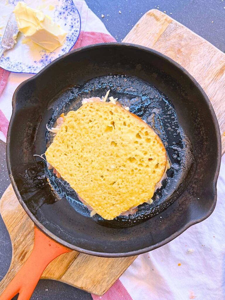 An egg dipped sandwich in a buttered frying pan.