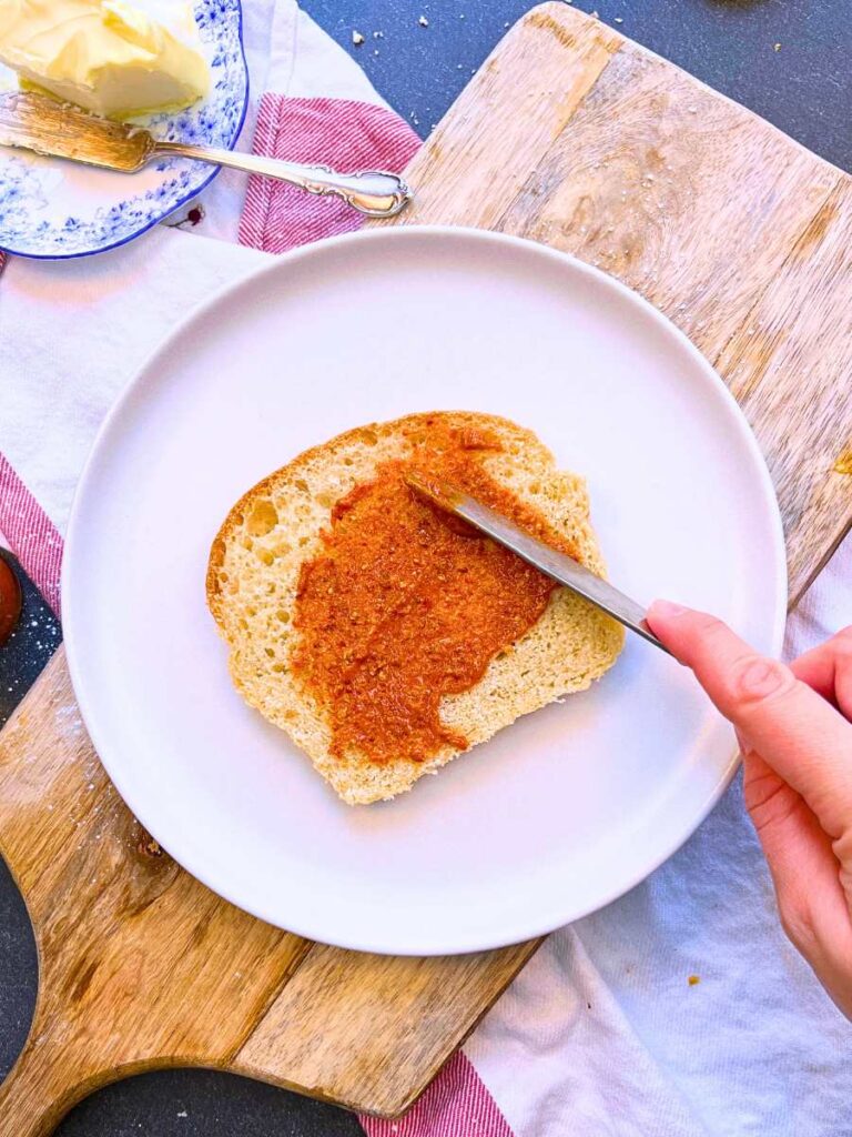 A woman is spreading a spicy mustard onto bread.