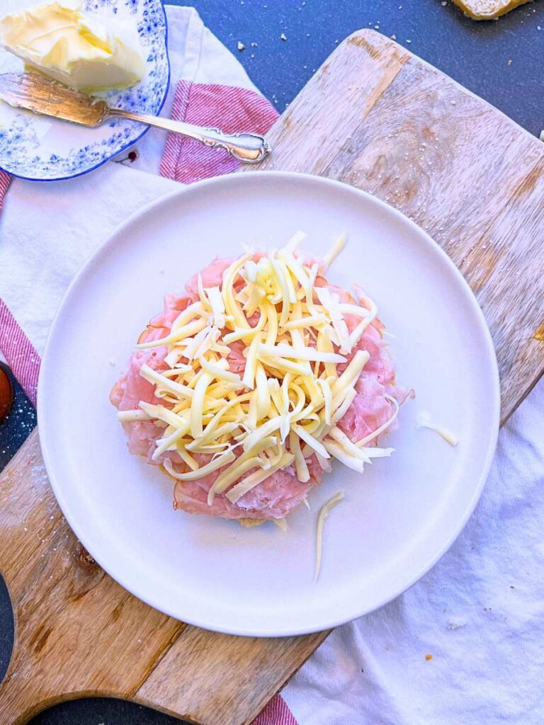 A slice of bread with deli ham and grated cheese.