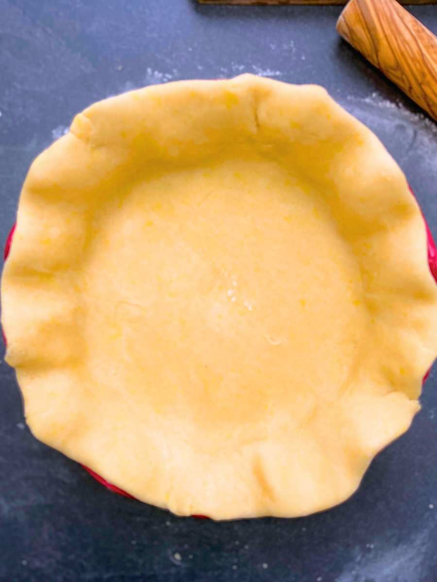 A lined and trimmed pie dough in a red pie plate.