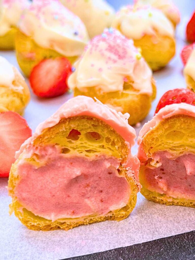 A profiterole split in half to show the strawberry cream inside.