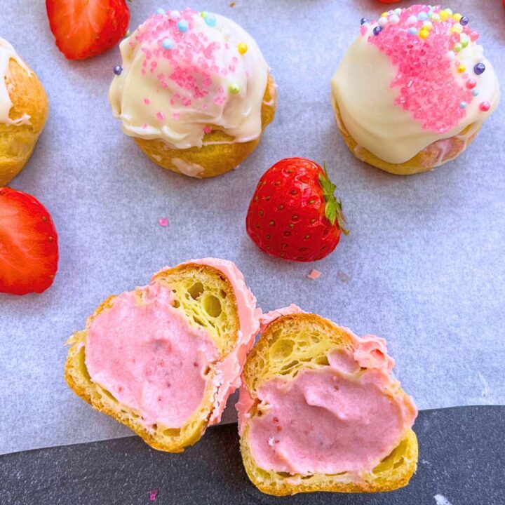 A profiterole split in half to show the interior strawberry cream.