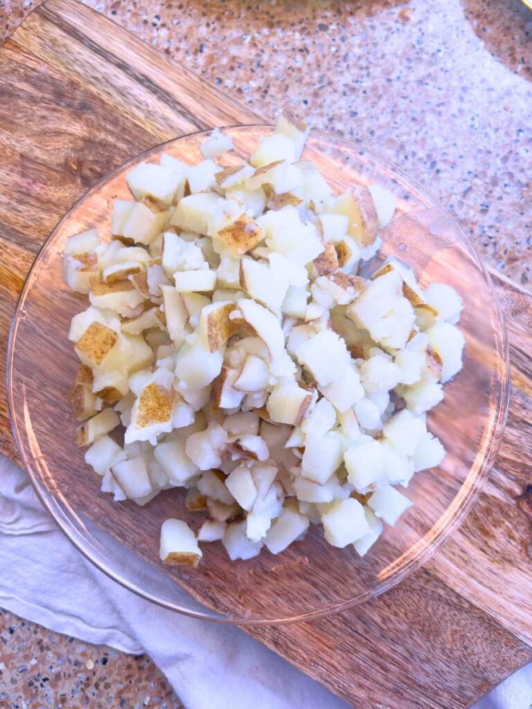 A glass plate filled with cooked potatoes cut in cubes.