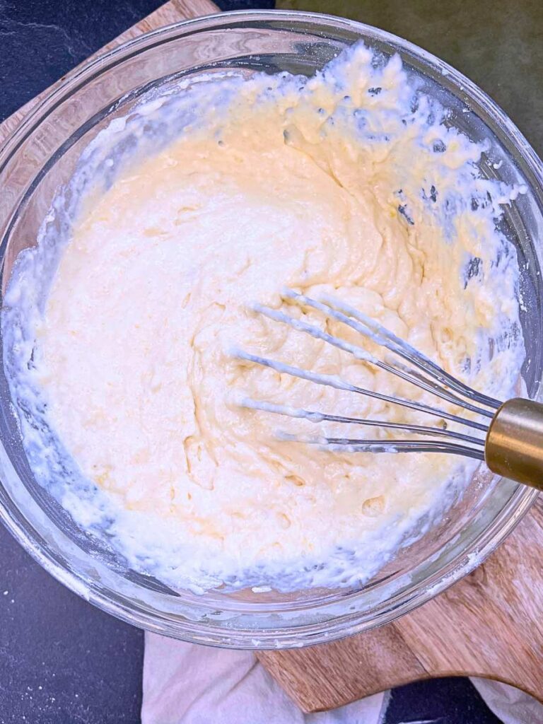Pancake batter in a glass bowl. There is a whisk inside the bowl.