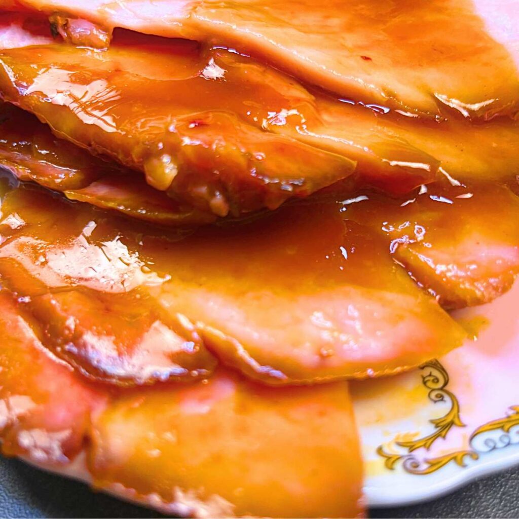 A close up look at slices of ham that are coated in a glaze.