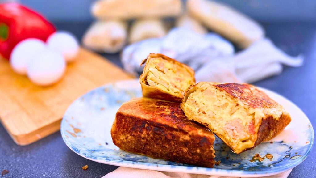 A breakfast wrap that has been cut to show the inside filling.. There are more in the background.