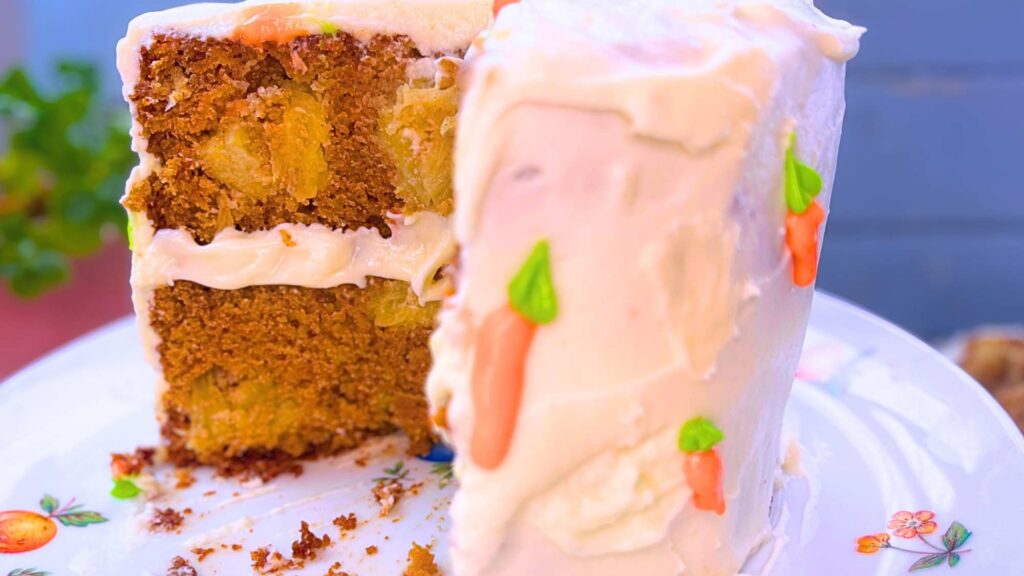 A carrot cake decorated with cream cheese icing and icing carrot decorations.