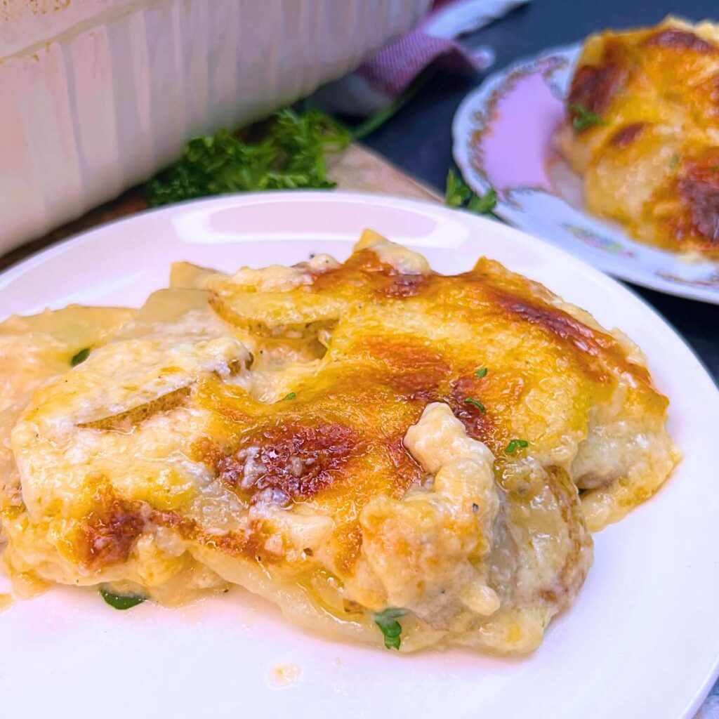 A small white plate with a serving of scalloped potatoes.