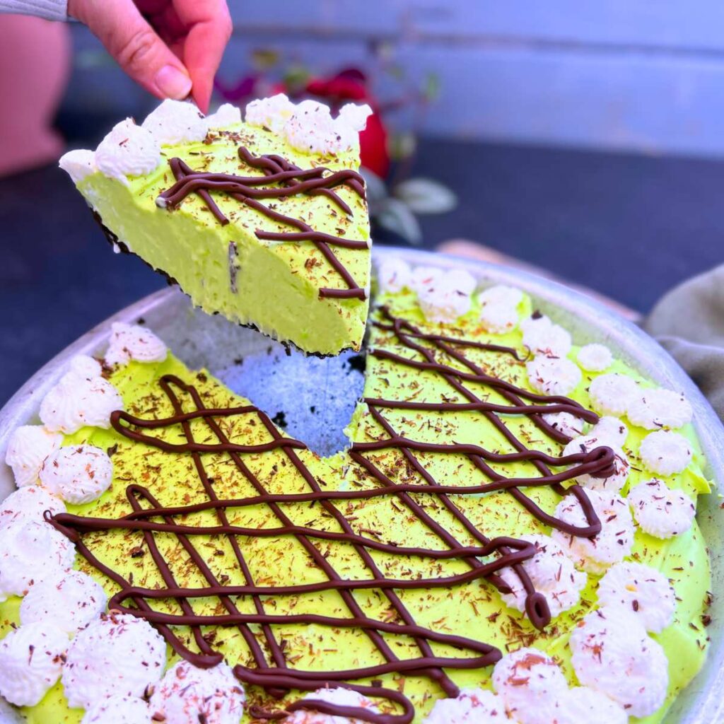 A woman is holding up a slice of grasshopper pie.