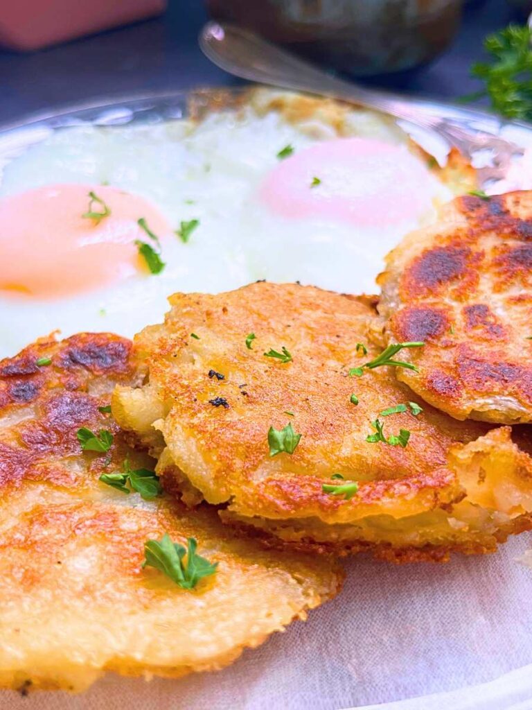 Three Irish potato boxty pancakes on a plate with two over easy eggs.