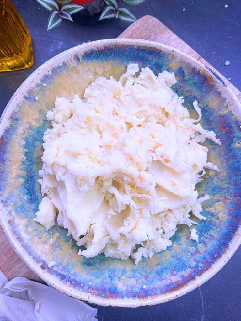 A mixture of mashed potatoes and grated raw potatoes in a bowl.