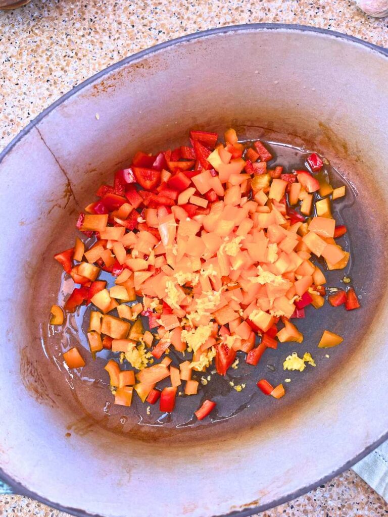 Chopped bell peppers and garlic in a Dutch oven.