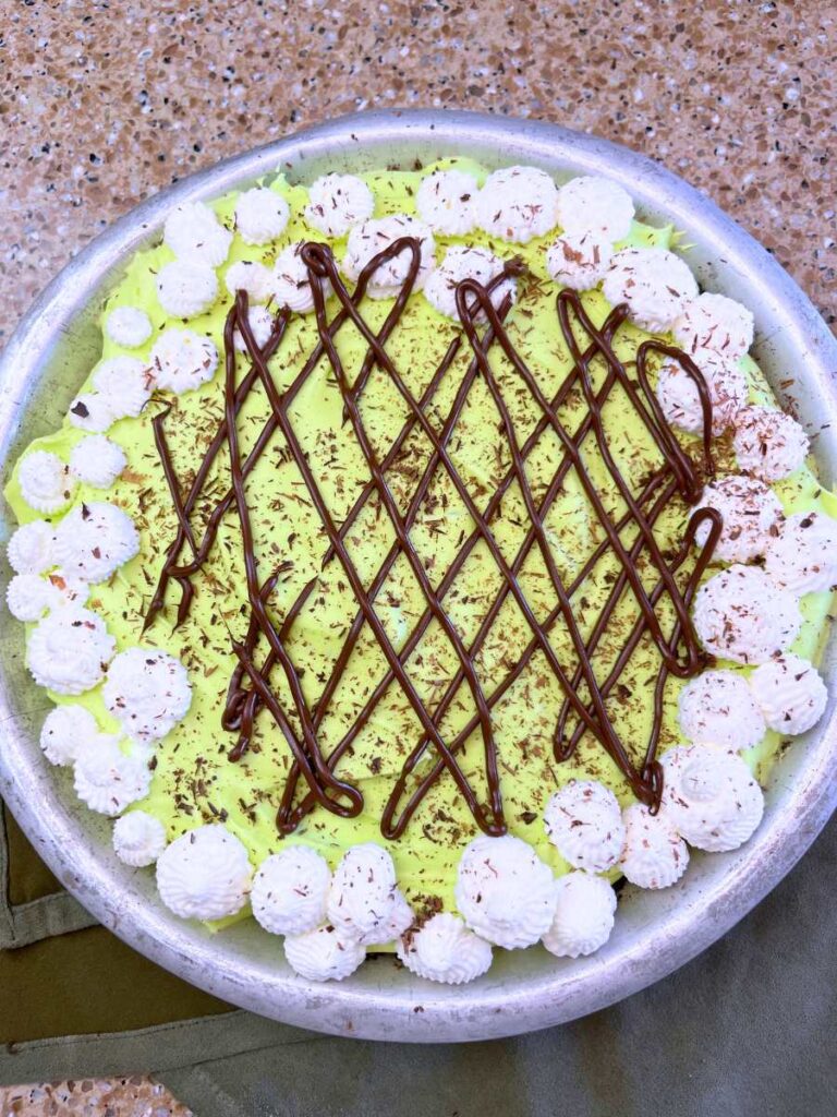 A decorated grasshopper pie with mint chocolate drizzle and whipped cream.