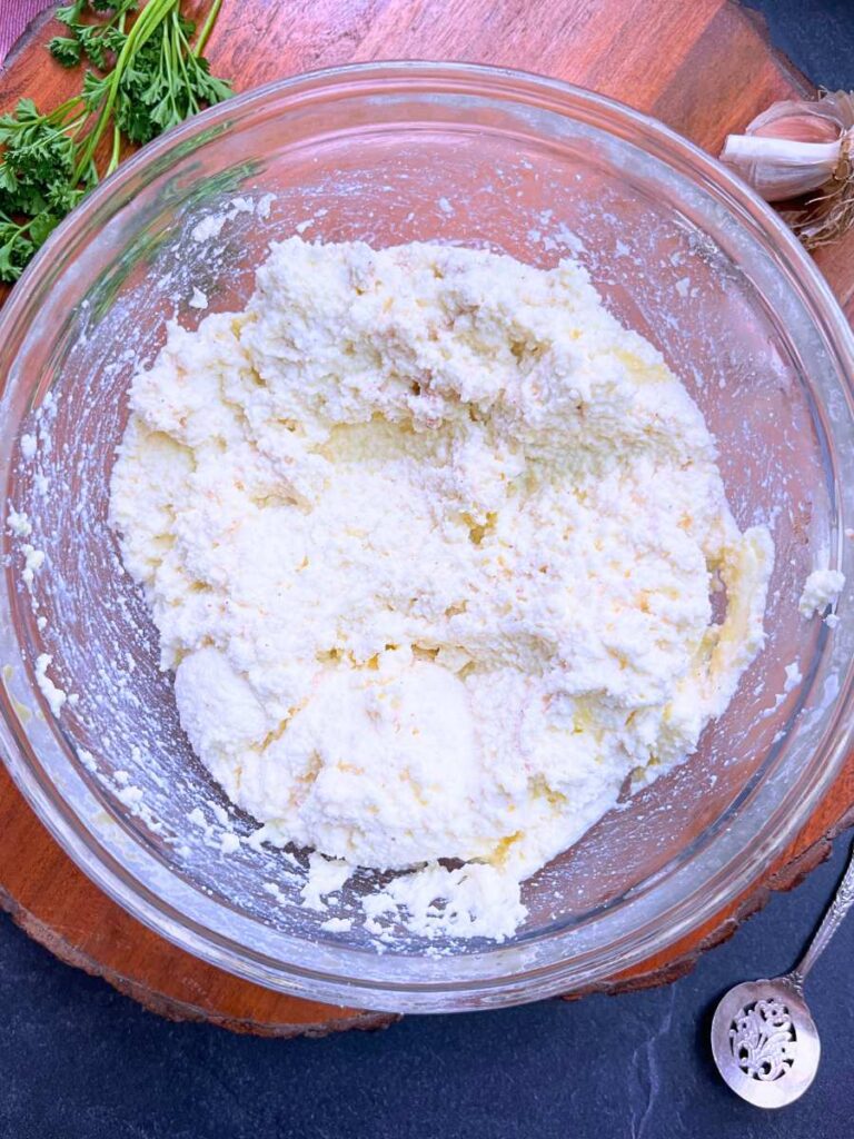 A clear glass bowl with ricotta cheese inside.