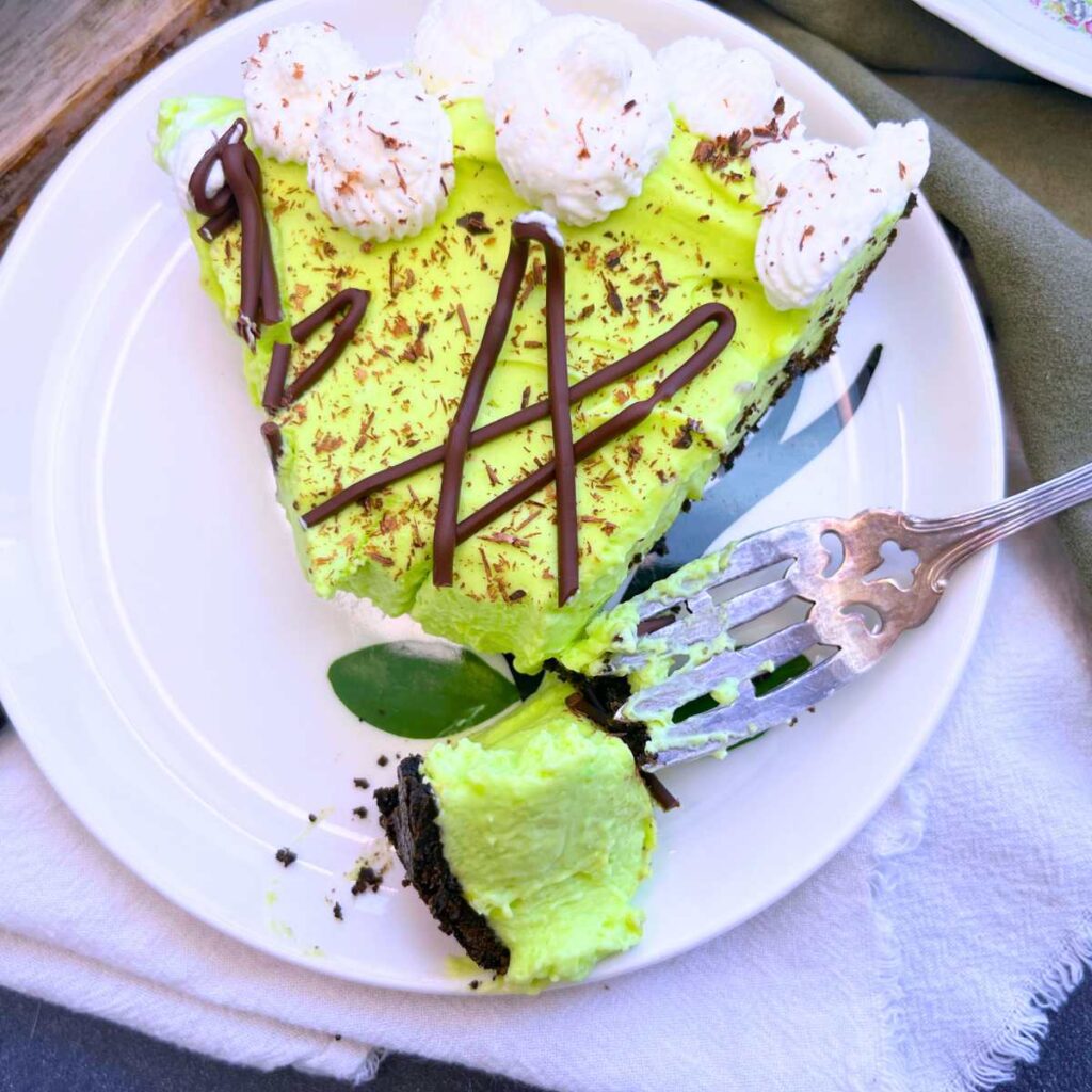 A slice of grasshopper pie on a white plate. There is a forkful cut at the end.