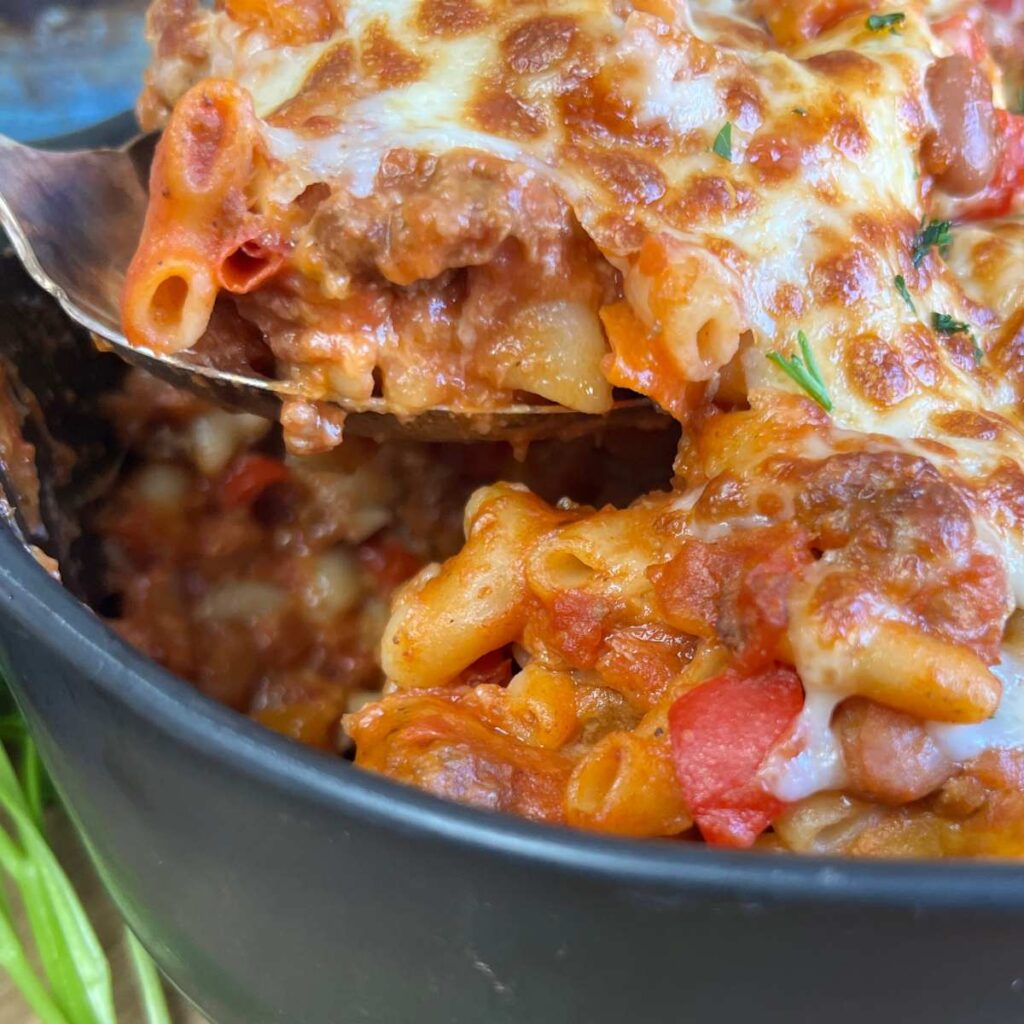 A baked casserole of chili mac and cheese in a black casserole dish.