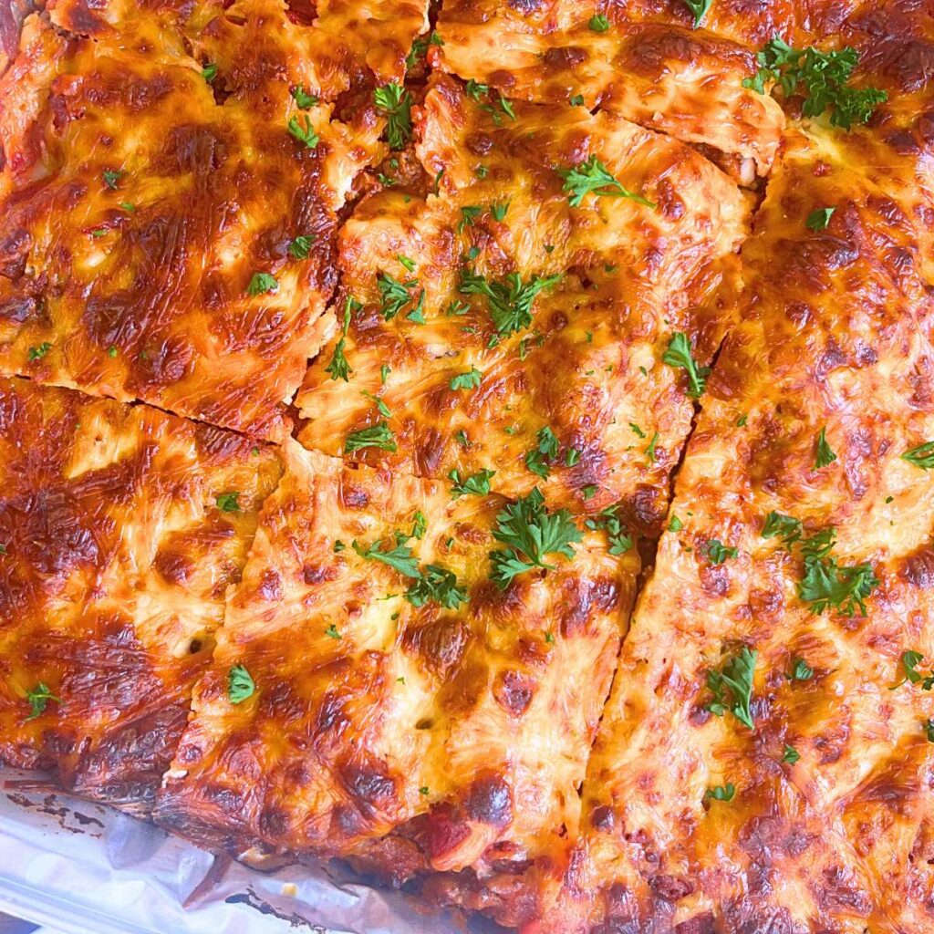 An over top view of a baked and sliced lasagna in a aluminum disposable pan.