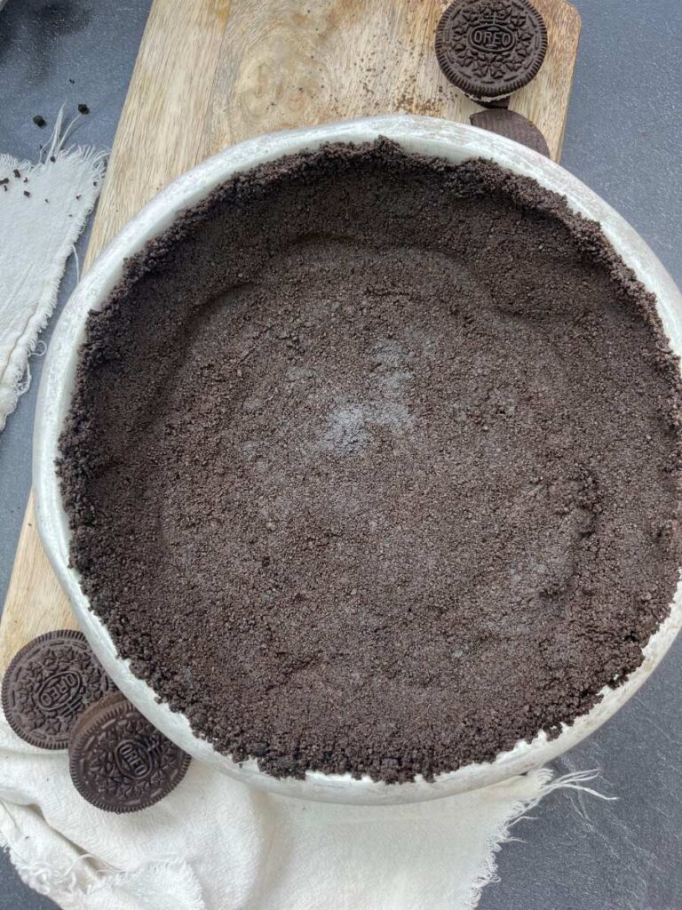 An Oreo cookie crust in a metal pie plate.
