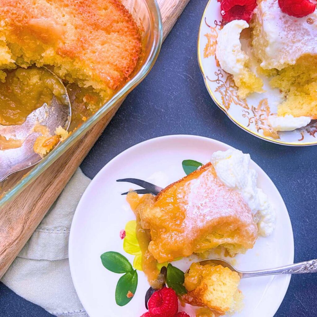 Two servings of pouding chômeur on small plates. There is more of the dessert in a square casserole dish off to the side.
