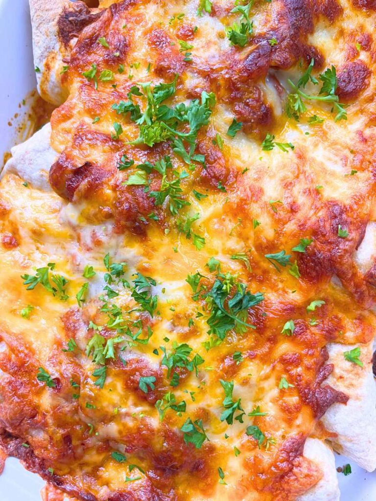 A white casserole dish with chicken enchiladas inside.