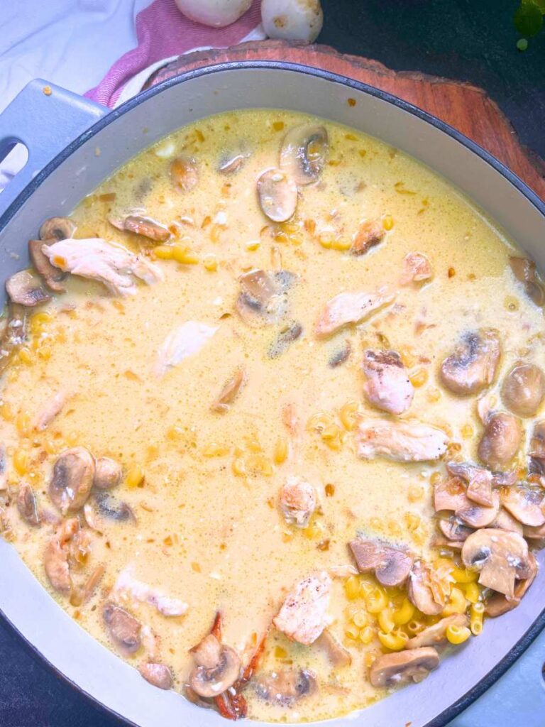 A grey Dutch oven with chicken, mushrooms, and a creamy broth inside.