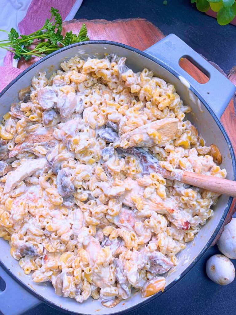 A grey Dutch oven with a cooked chicken stroganoff pasta inside.