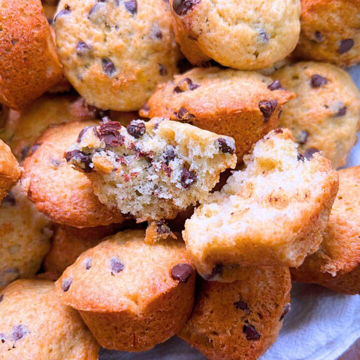A collection of mini banana chocolate chip muffins. Once is split in half.