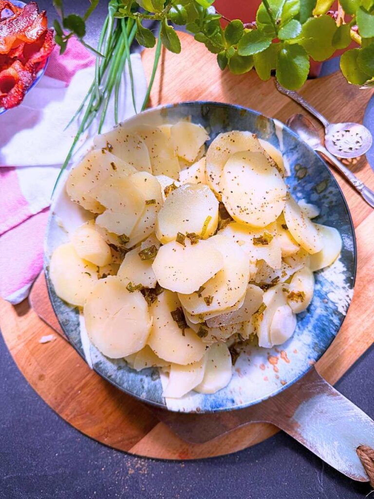 Sliced cooked potatoes with a warm vinegar dressing on top.