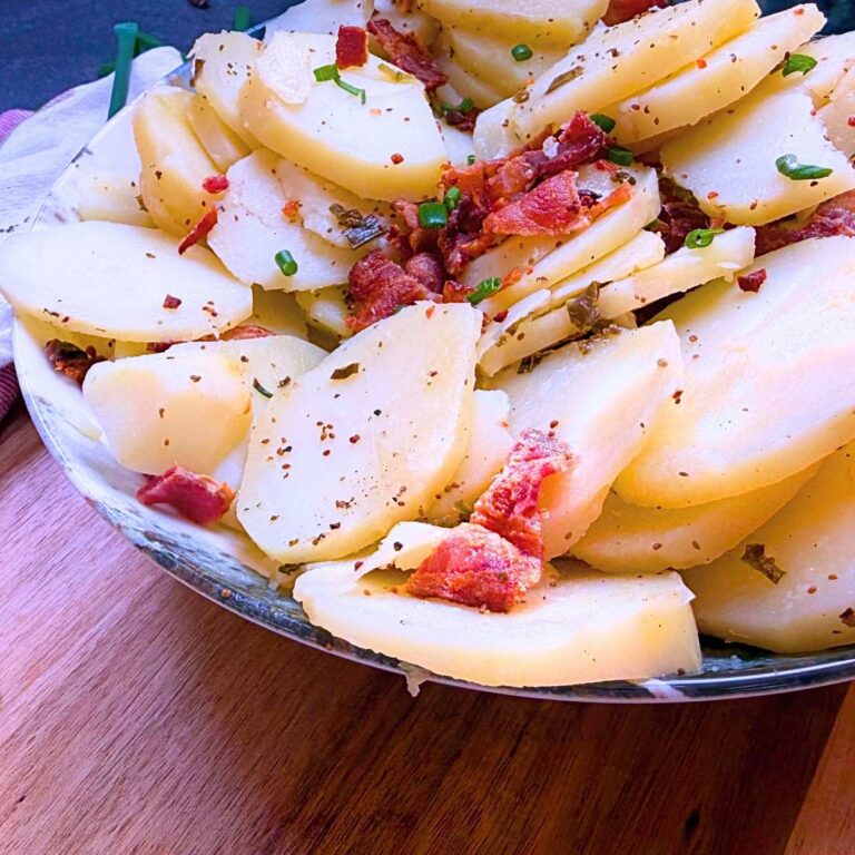 A side view of a German potato salad with bacon and chives.