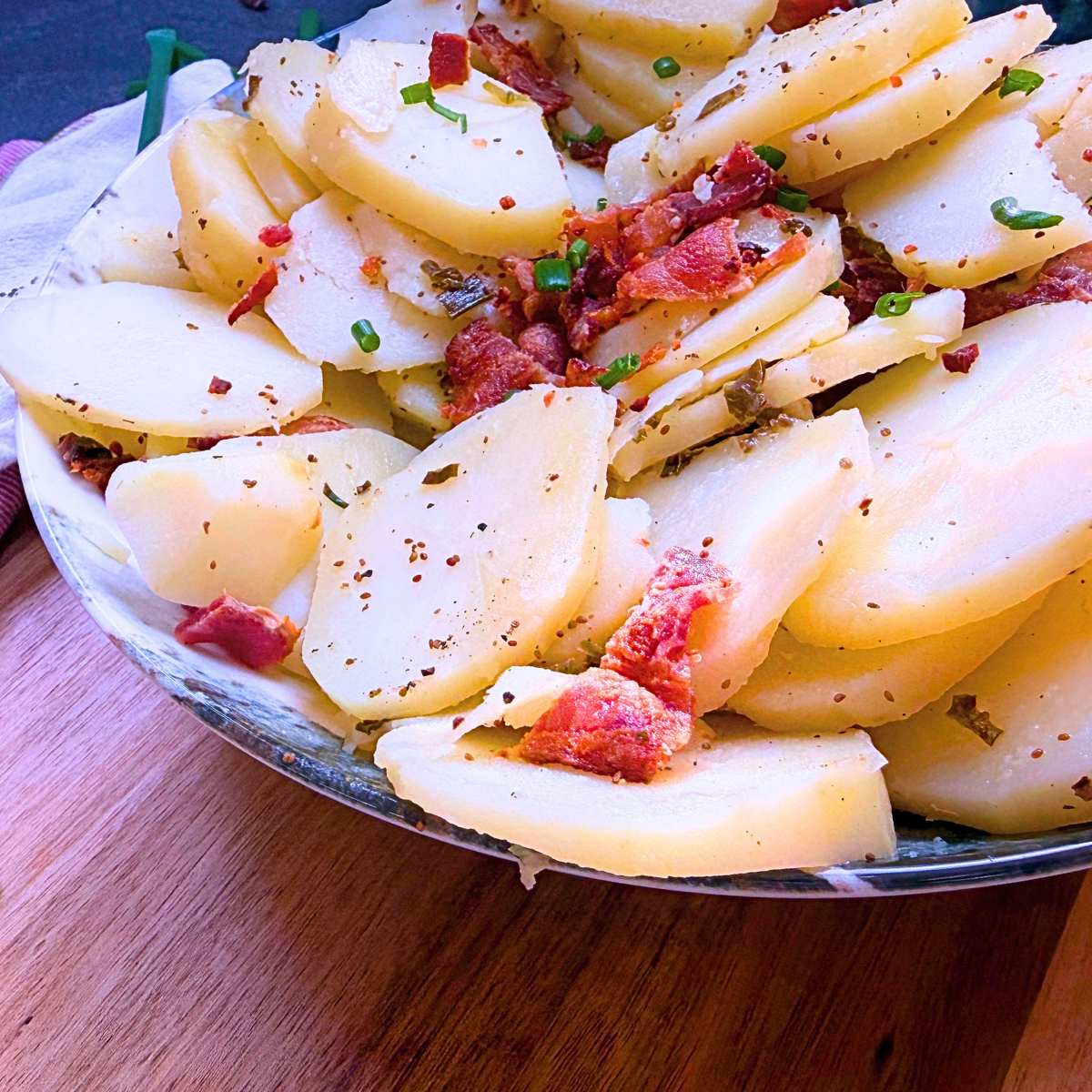A side view of a German potato salad with bacon and chives.