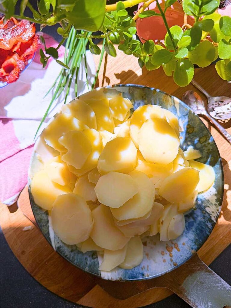 Sliced cooked  potatoes in a large blue bowl.