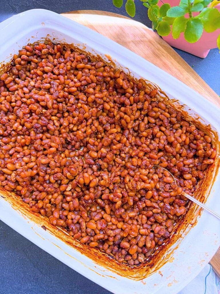 A white casserole dish of baked beans.