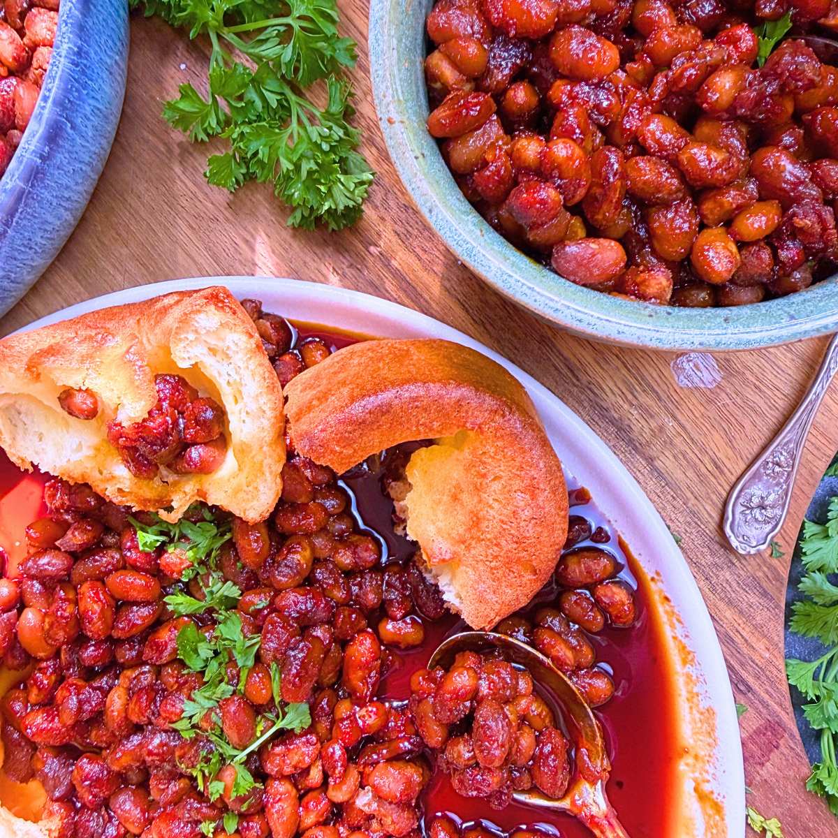 Three dishes filled with baked beans. There is a popover on the white plate.