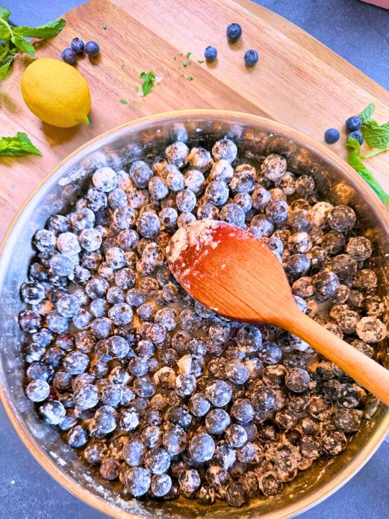 A metal pan filled with blueberries coated in sugar and cornstarch.