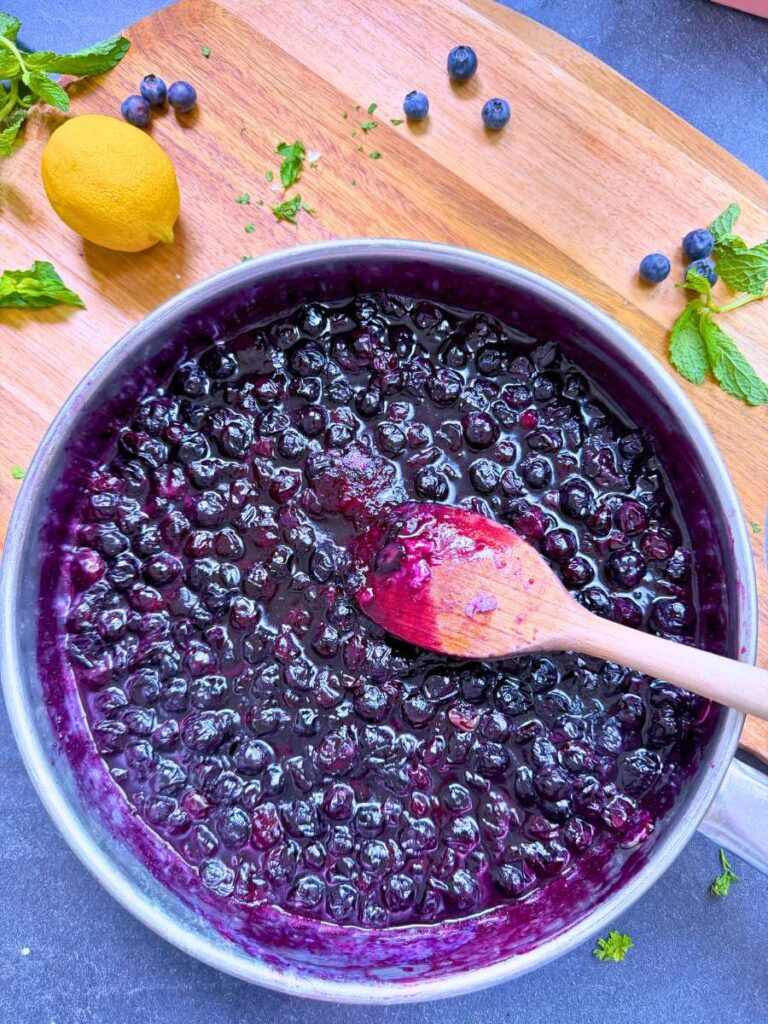 A cooked blueberry sauce in a metal pan.