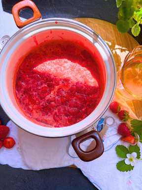 A white sauce pot with mashed strawberries inside.