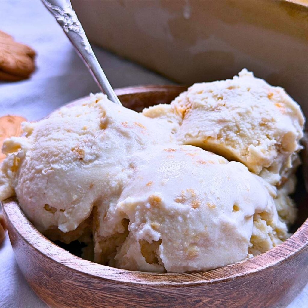A wooden bowl with three scoops of maple ice cream inside.