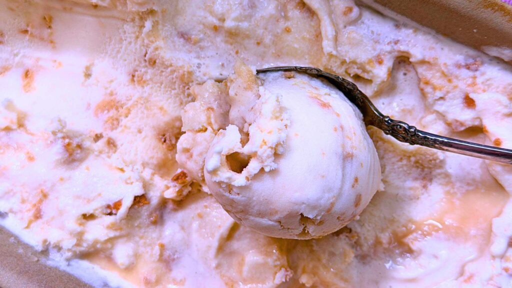 A container of homemade maple ice cream with a spoonful resting on top.